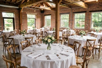 Salle de mariage décorée pour 100 invités avec tables rondes, nappes blanches et centres de table floraux simples